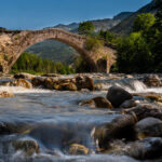 low-angle-shot-old-arch-bridge-with-river-it-during-daylight (1)